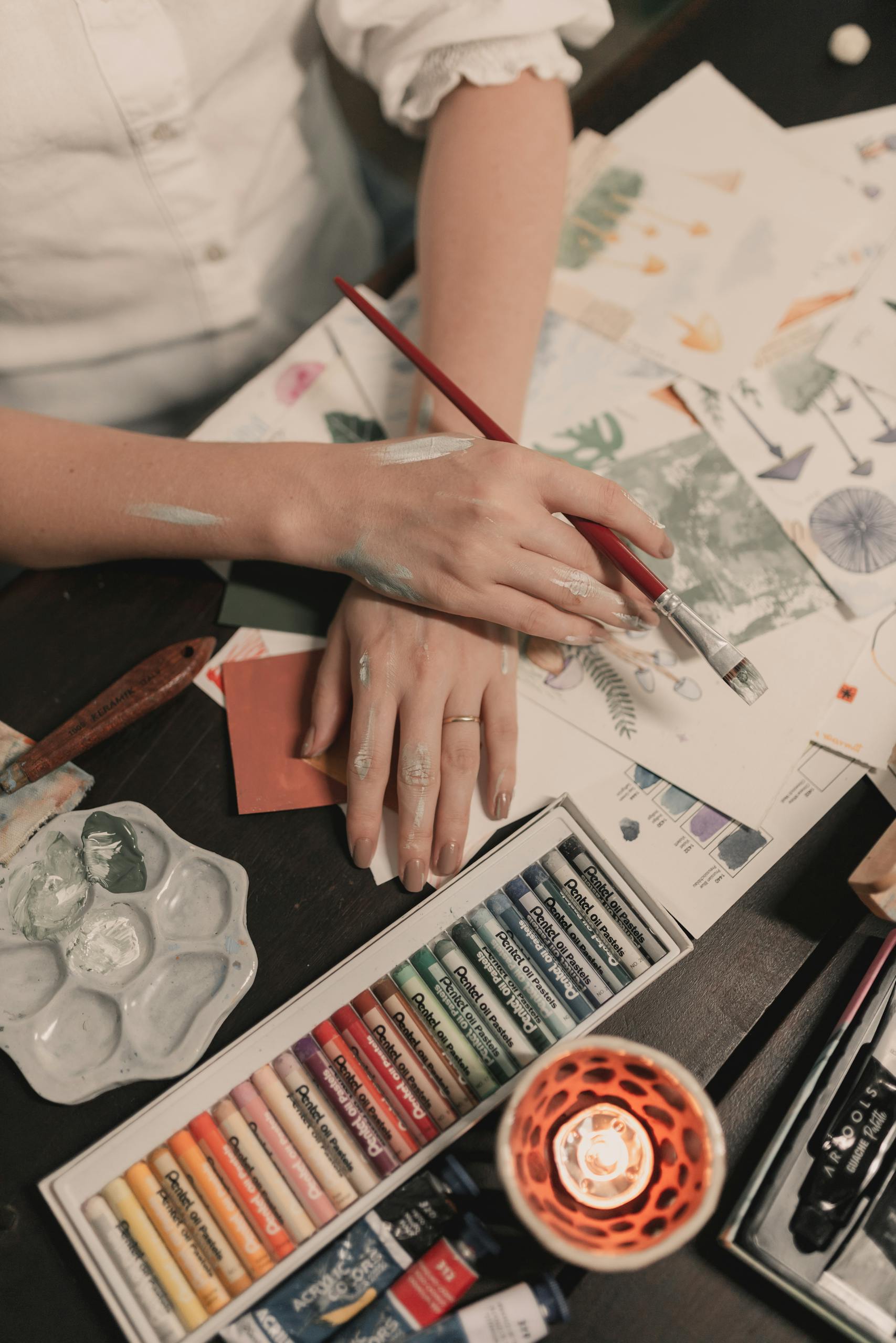 A creative setup with oil pastels, paintbrush, and artwork, perfect for artistic inspiration.